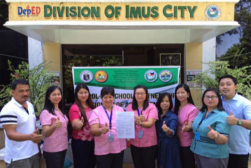 Mrs. Gina U. Reyes (5th from left) , principal of Alapan I ES, and Mrs. Marcelina D. Naputo (4th from left), principal of Bukandala ES, raise their signed agreement with a thumbs up sign together with some Division personnel and other witnesses.